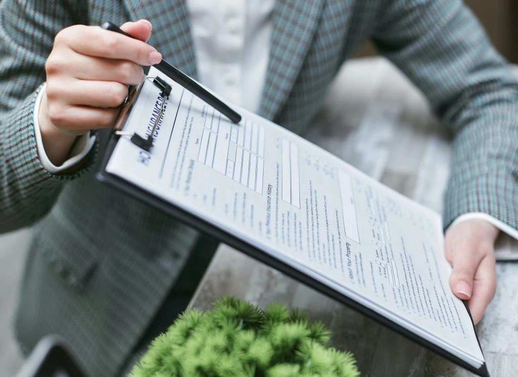 Insurance agent holding clipboard pointing out terms and conditions with his pen