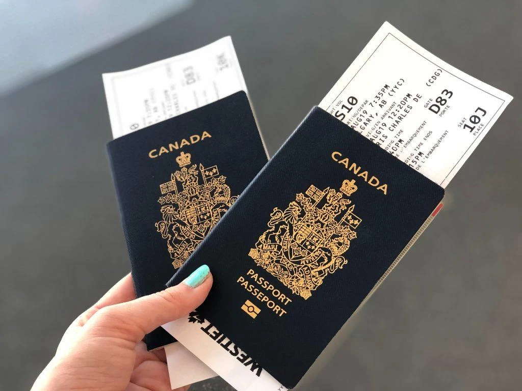 woman holding two canadian passports stuffed with airline boarding passes